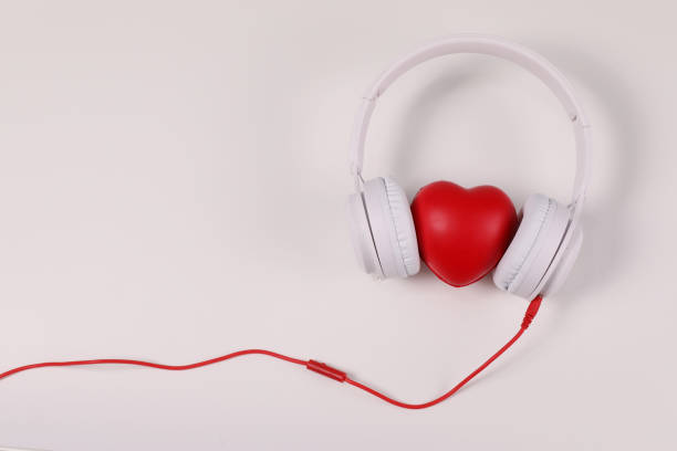 white headphones with red heart sign in the middle on white surface. - 语音交护 個照片及圖片檔